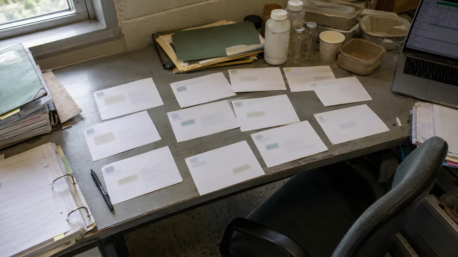 Acquisition planning desk with twelve blank category cards, sample containers, and messy compliance folders